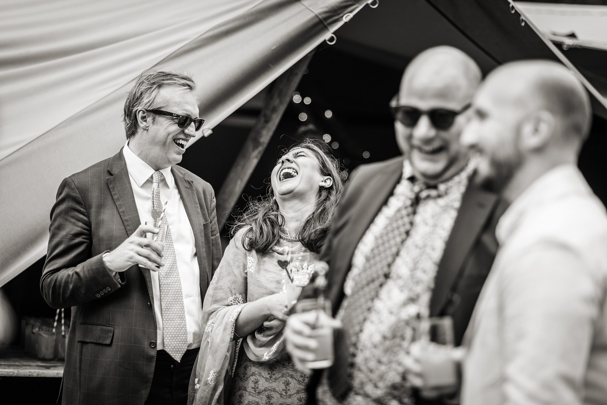 Laughing and relaxed guests at a marquee wedding celebration