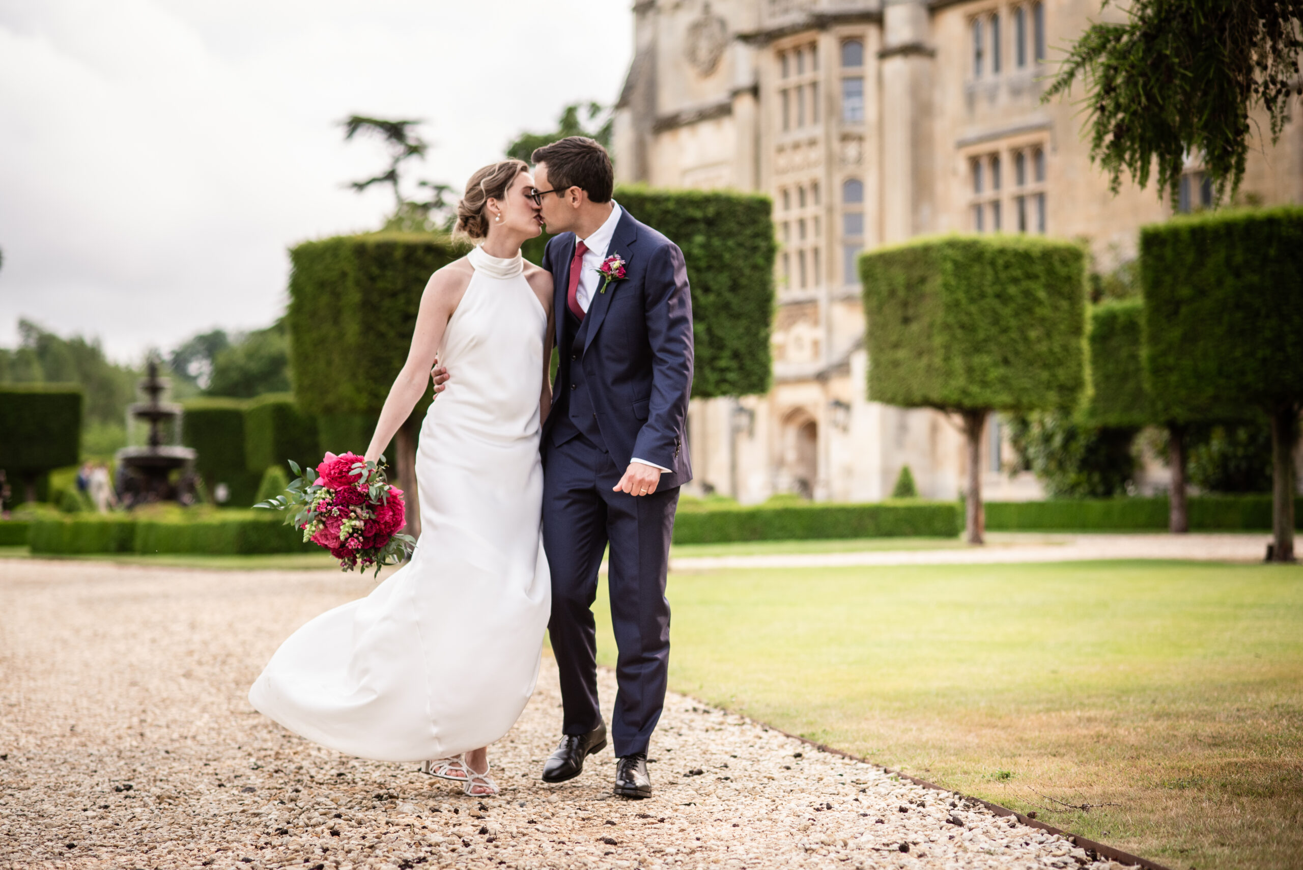 Bride and groom walk and kiss together in the grounds of Farleigh House